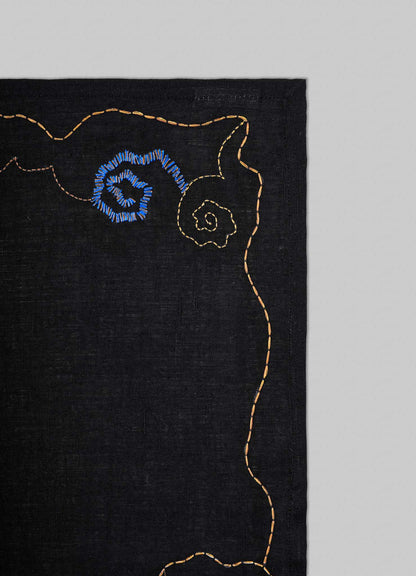 Black fabric with embroidered blue floral design on a gray background viya placemats