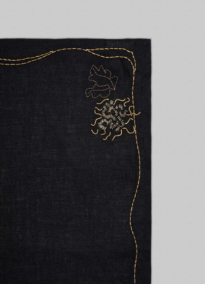 Black fabric with gold embroidery on a gray background viya luxury placemats