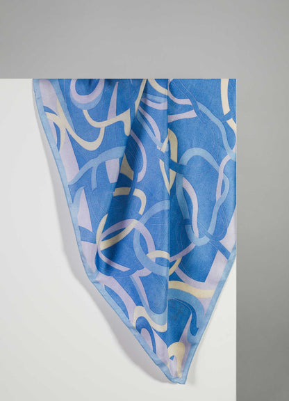 A silk scarf featuring an abstract, flowing pattern in shades of blue, lavender, and cream, displayed against a light gray background.