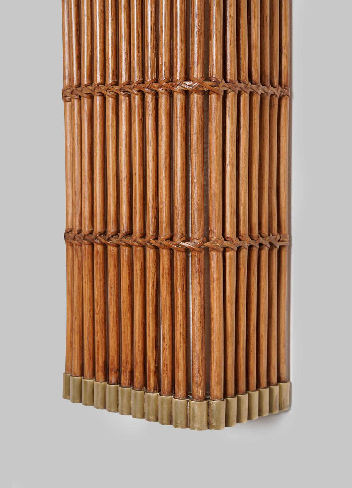 A close-up of the VIYA Namsai Wall Sconce, featuring vertically aligned wooden rods bound together with dark thread using traditional Indian techniques, ending with a row of metal caps at the bottom, set against a plain light gray background.