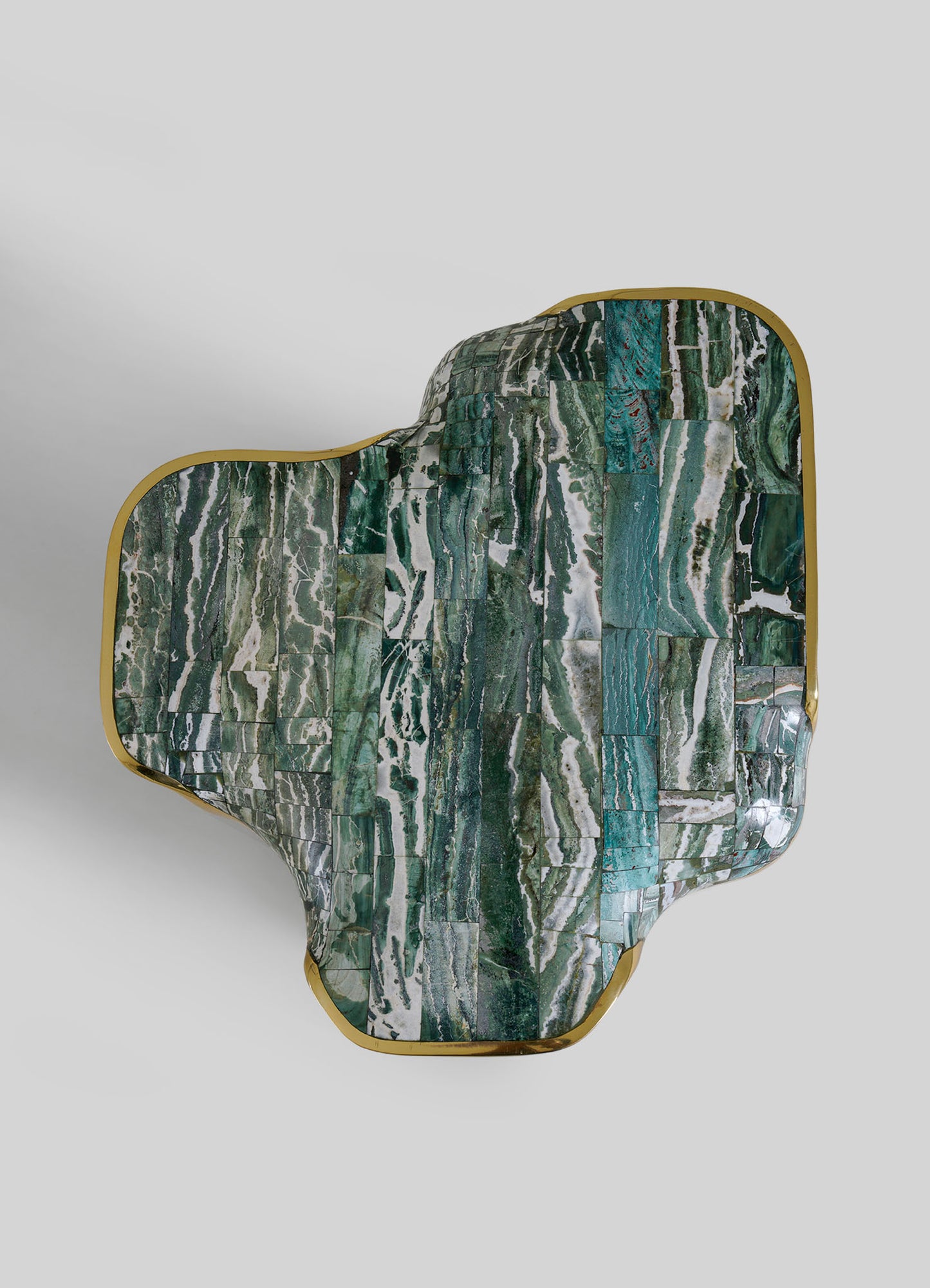 The VIYA Coonoor Side Table features an abstract, organic shape with a glossy green and white marbled top inspired by Indian landscapes, accented by a gold metallic trim along the irregular edge, set against a light gray background.