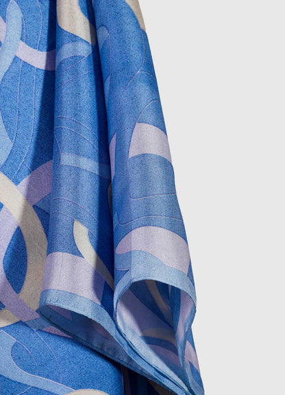 A close-up of a fabric curtain with an abstract geometric pattern in shades of blue and light purple. The material appears to be lightweight with a soft drape, emphasizing a modern or contemporary style.