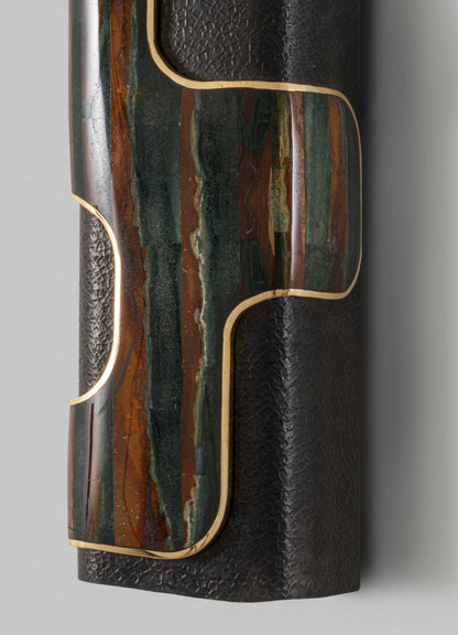 A decorative table visible in the image, featuring a top surface with a multicolored, abstract pattern in shades of green, brown, and cream, framed by a thin gold trim. The main body appears to be made of black textured material, possibly leather or faux leather, with a subtle pattern.