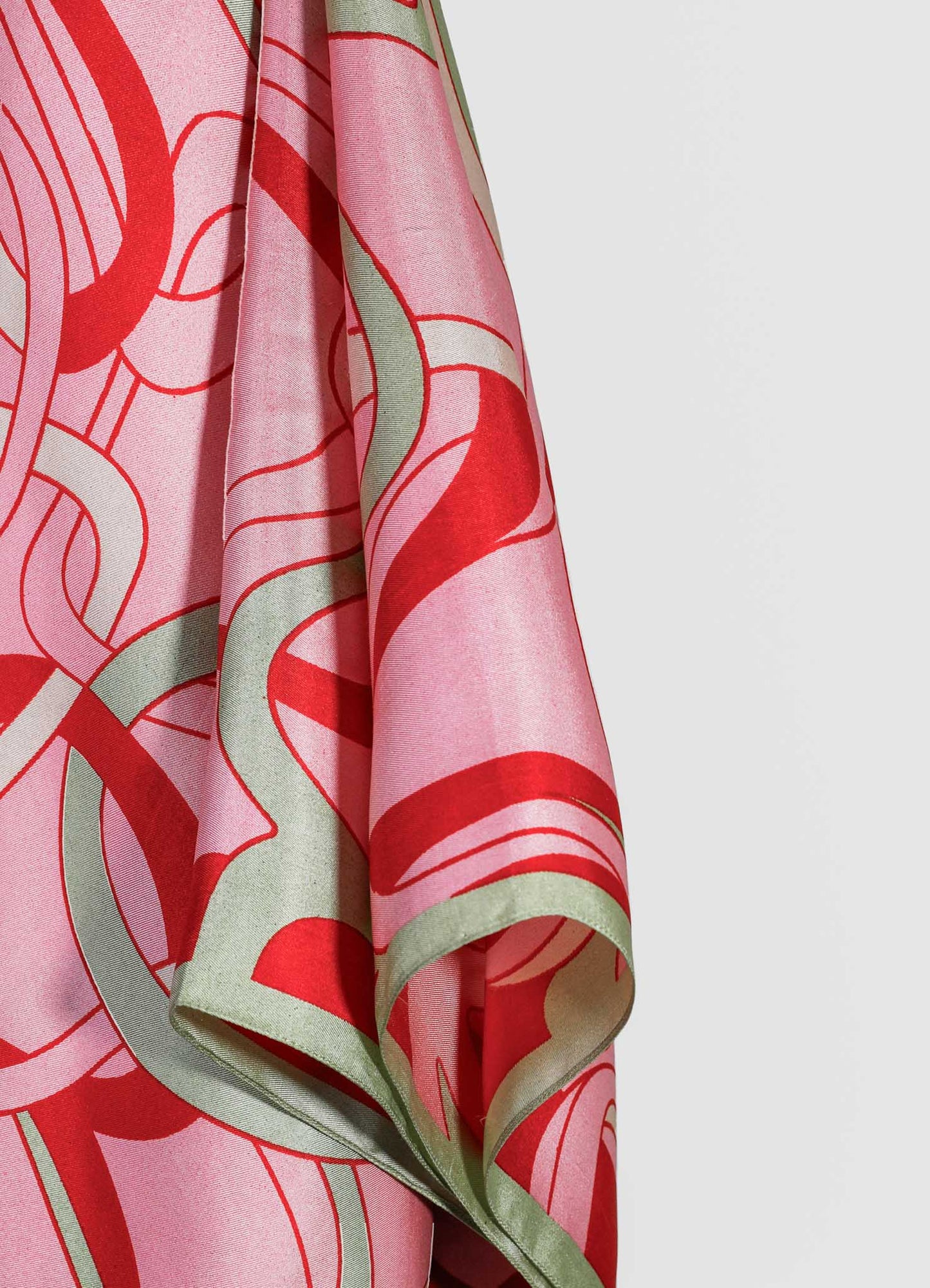 A silk scarf featuring a bold, abstract floral pattern in shades of pink, red, and pale green, with flowing, organic motifs and a satin finish.