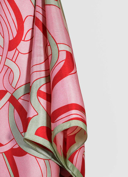 A silk scarf featuring a bold, abstract floral pattern in shades of pink, red, and pale green, with flowing, organic motifs and a satin finish.