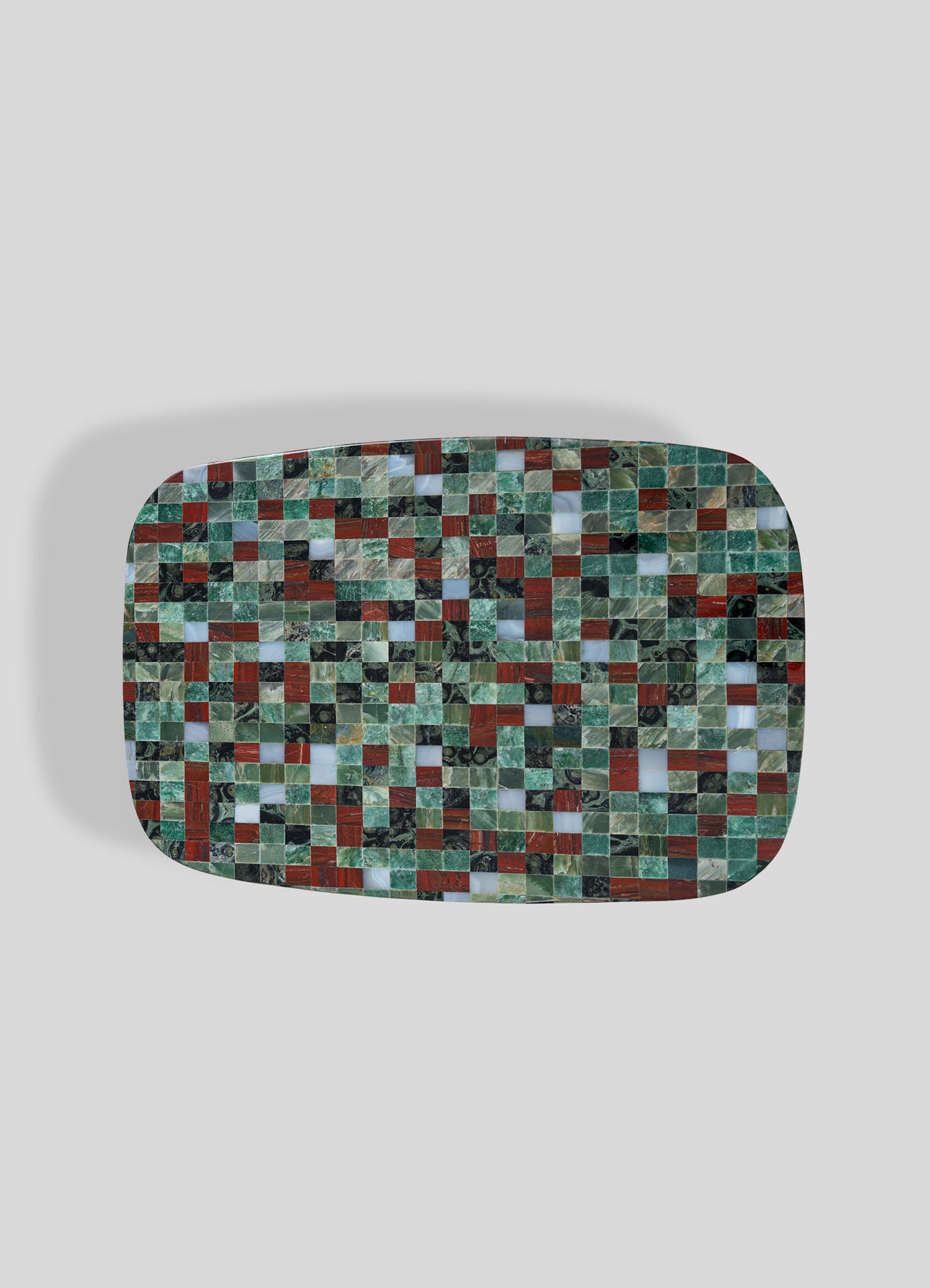 The VIYA Mosaic Red Side Table features a rectangular design with rounded edges and showcases a vibrant mosaic pattern of small square tiles in green, red, and black—evoking the look of terrazzo furniture—all set against a plain light gray background.