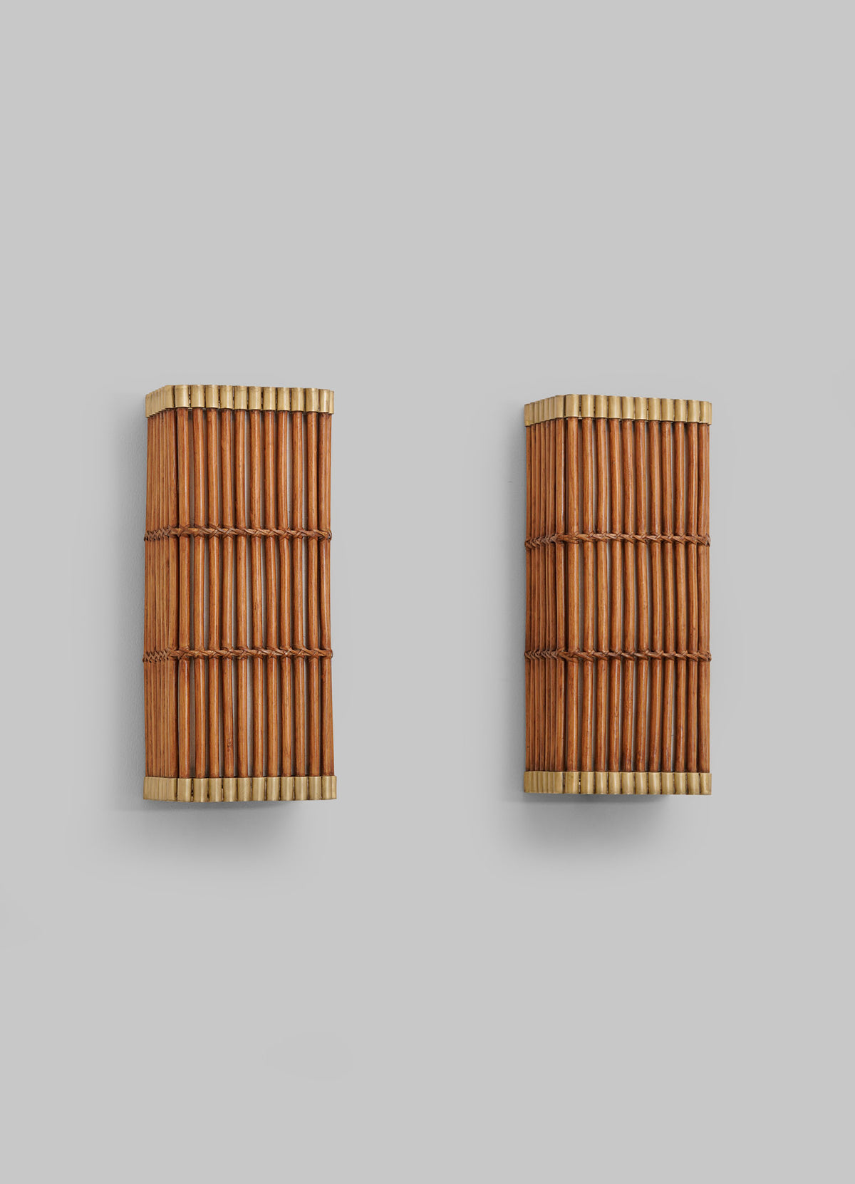Two Namsai Wall Sconces by VIYA, crafted from vertical bamboo rods and framed in light-colored wood, are mounted on a plain gray wall, exemplifying the charm of handcrafted lighting inspired by traditional Indian techniques.