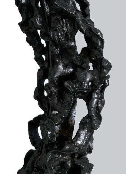 Close-up of the VIYA Andaman Mirror, featuring an abstract, dark metallic frame with rough, irregular, cave-inspired surfaces against a plain light gray background.