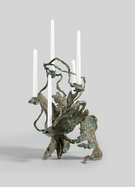 The VIYA Butterfly Candle Stand Large is a sculptural bronze candelabrum with an organic, abstract design, finished in greenish-bronze patina, holding four tall white candles against a plain light gray background.
