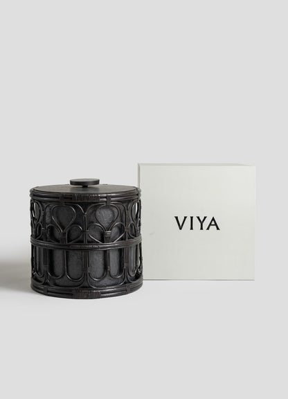 The VIYA Manipur Ice Bucket Large, a round, dark-toned container with a detailed hand-beaten brass design and lid, sits beside a simple white box labeled VIYA in bold black letters.