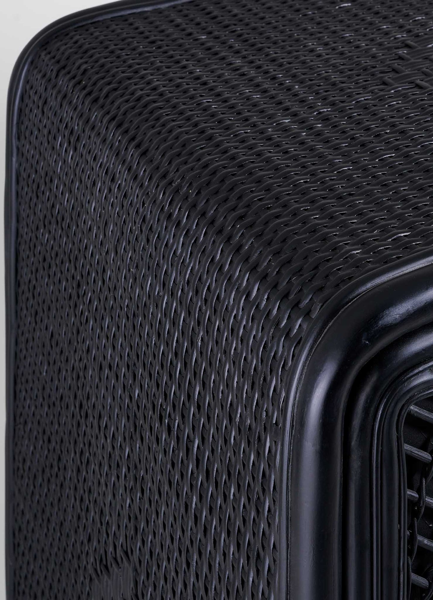 Close-up of the corner of VIYA's Chakra Cabinet, showcasing its black, textured, woven-patterned finish reminiscent of cane weaving, with a vent or grille visible on the right side.