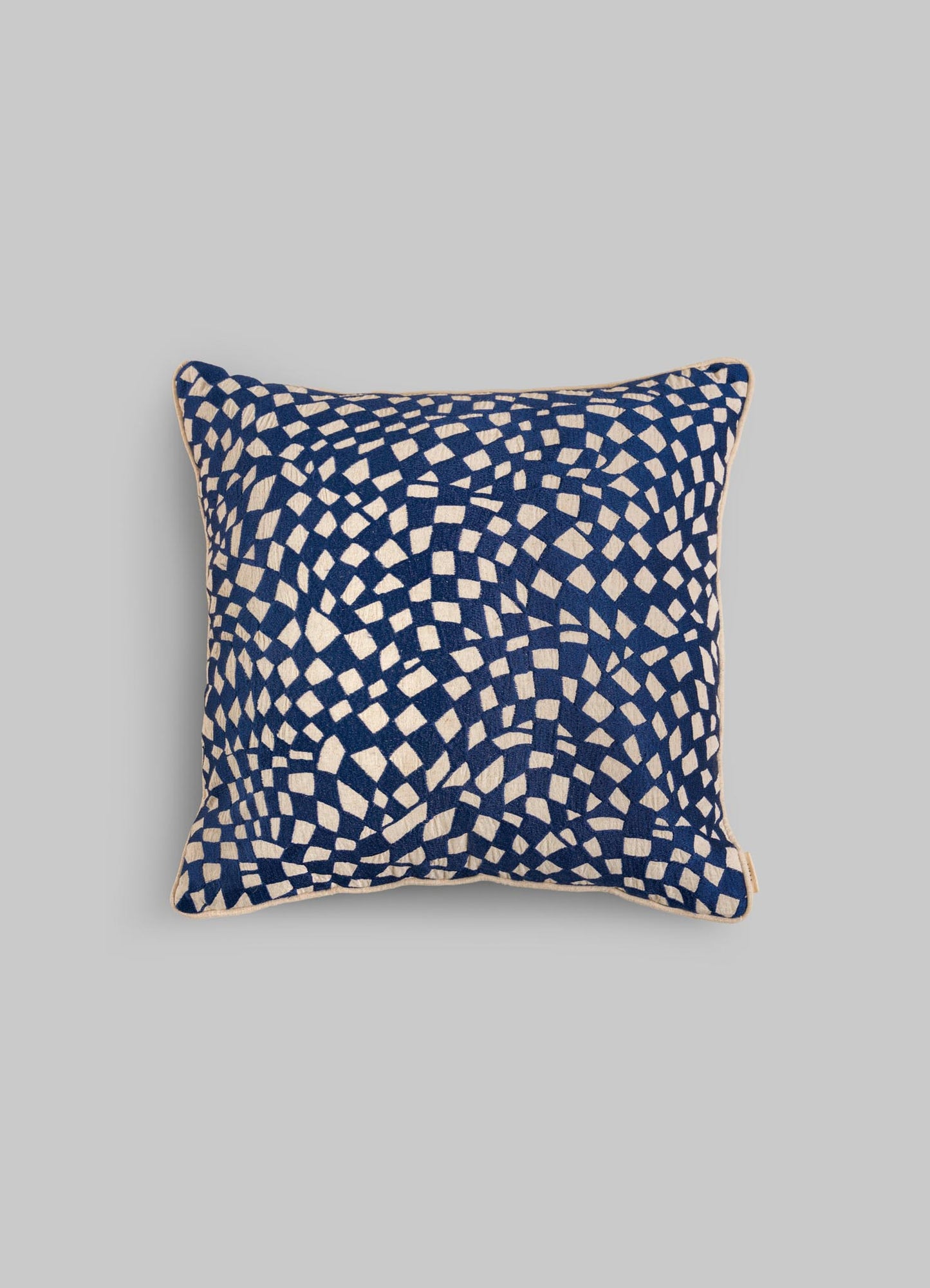 The Viya Dreamscape Blue Embroidered Checks Cushion Cover (18"x18") features an abstract white check pattern on a dark blue background, inspired by textile motifs, shown against a plain light grey backdrop.