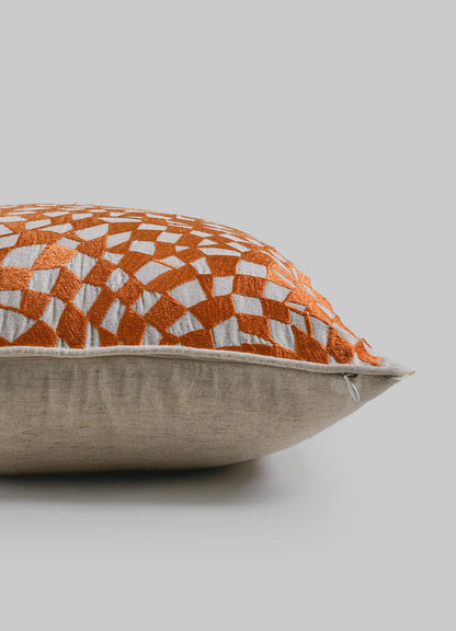 The Viya Dreamscape Orange Embroidered Checks Cushion Cover 18"x18" features a beige base with an orange geometric motif, shown side view on a gray background.