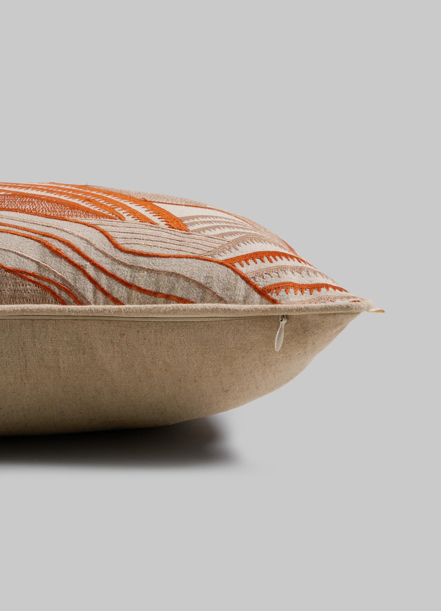 The Viya Dreamscape Orange Embroidered Mounds Cushion Cover (12"x18") features a beige base with orange geometric motif embroidery and a visible zipper, displayed side view on a plain gray background.