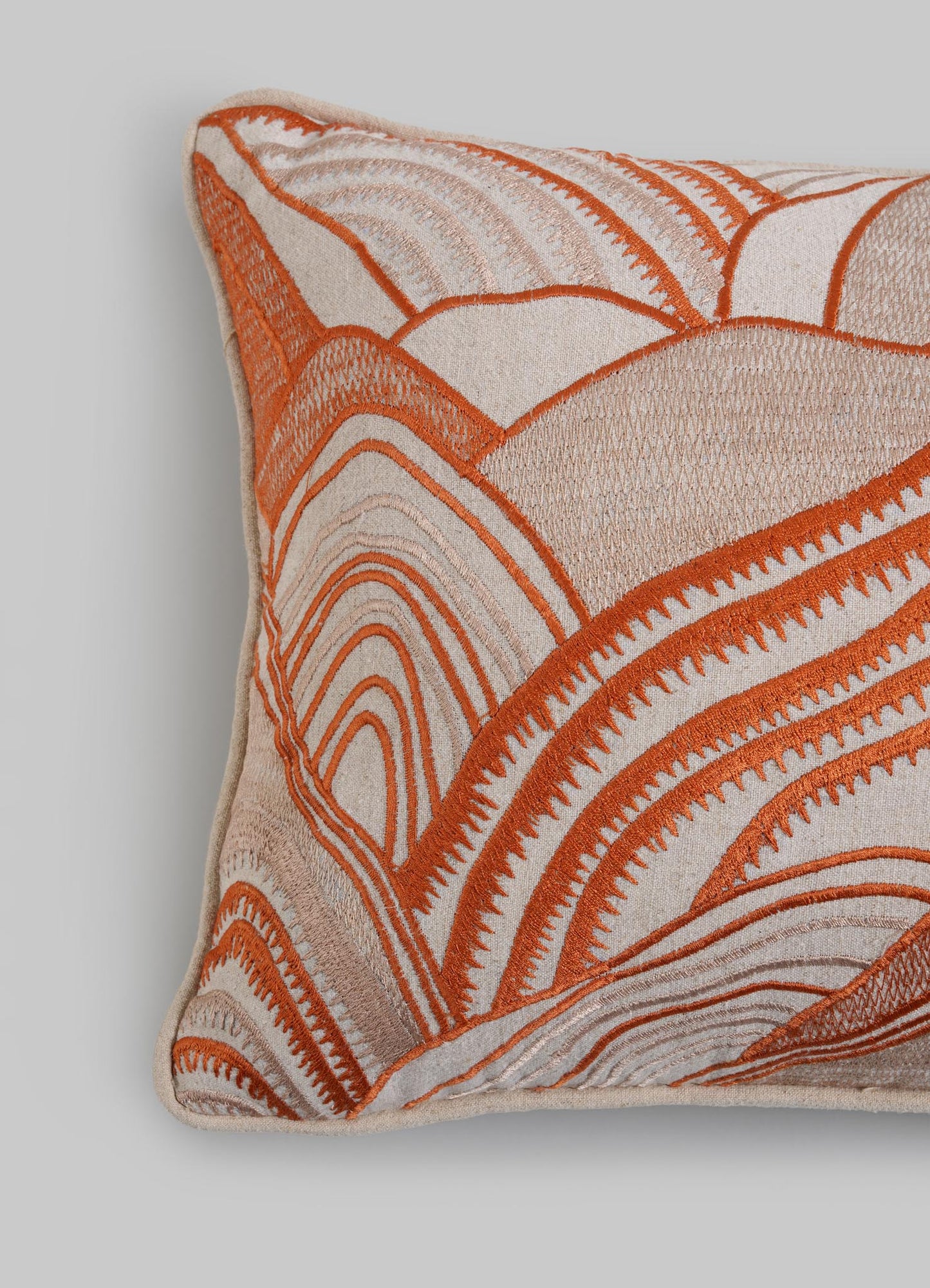 The Viya Dreamscape Orange Embroidered Mounds Cushion Cover 12"x18" features cream fabric with an abstract orange and beige embroidered pattern of curved, layered lines on a plain light grey background.