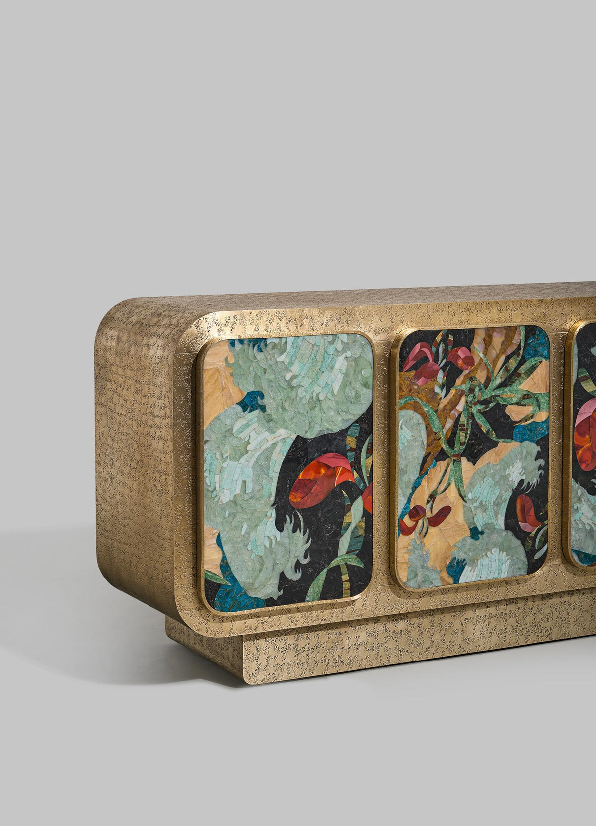 The VIYA Gardens Of India Cabinet is a rectangular sideboard with a textured gold finish, three front panels featuring colorful abstract botanical designs, rounded edges, and a light gray background inspired by Indian gardens.