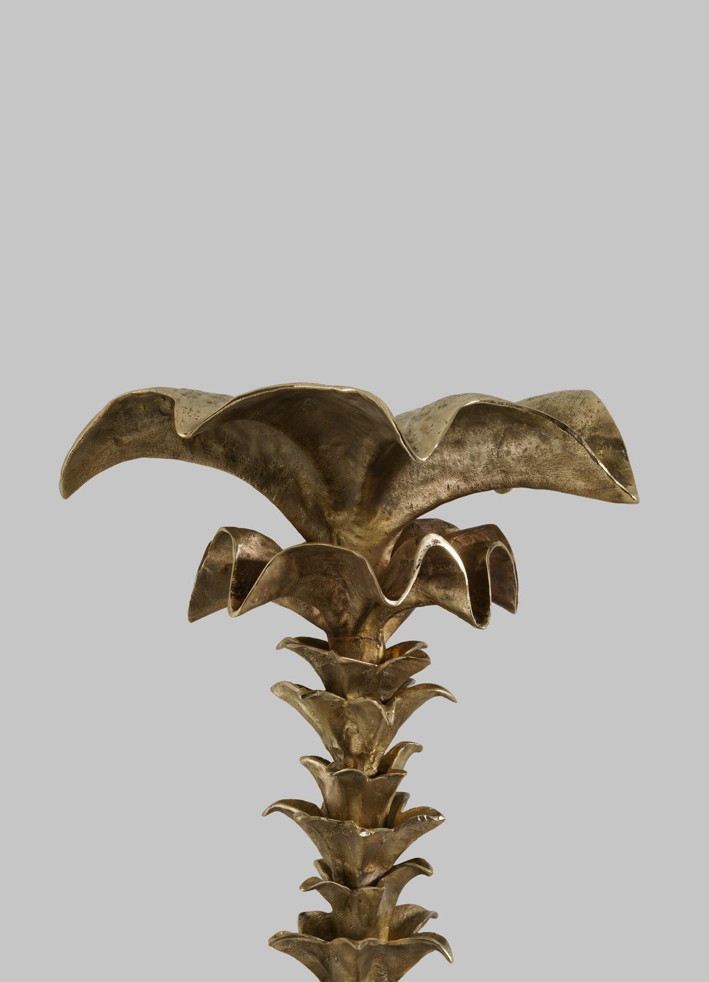 The VIYA Indian Vessel Finial is a metallic sculpture with stylized, layered petals and a shiny gold finish, inspired by brass vessels. Set against a light gray background, it’s perfect for adding Indian flair to any space.