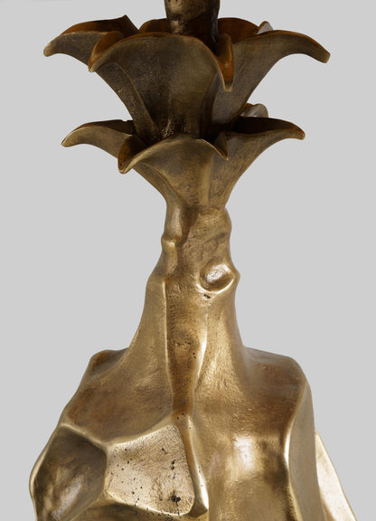 Close-up of the VIYA Indian Vessel Table Lamp, featuring a sculpted metallic form inspired by traditional brass lota vessels, with curved petals and a textured golden-bronze finish set against a plain gray background.