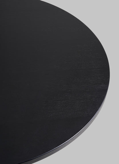 A close-up of the edge of the round, black Kikar Dining Table by VIYA, part of our desert collection, set against a plain gray background.
