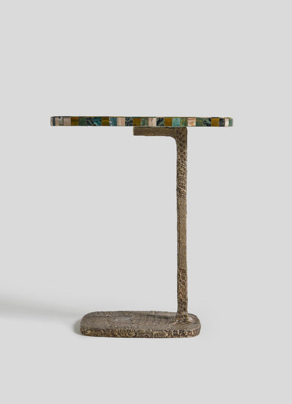 The VIYA Mosaic Side Table A is a small table with a textured cast brass base and a round, multicolored semi-precious stone top, shown against a plain light gray background.