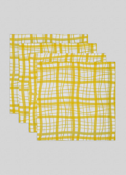 The Viya Madras Check Yellow Napkins—Set of 4 features a yellow and white checkered pattern, inspired by Indian textiles. Each napkin is stacked with edges slightly visible, displayed on a light grey background.