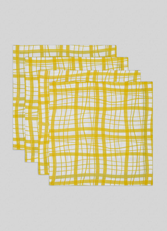 The Viya Madras Check Yellow Napkins—Set of 4 features a yellow and white checkered pattern, inspired by Indian textiles. Each napkin is stacked with edges slightly visible, displayed on a light grey background.