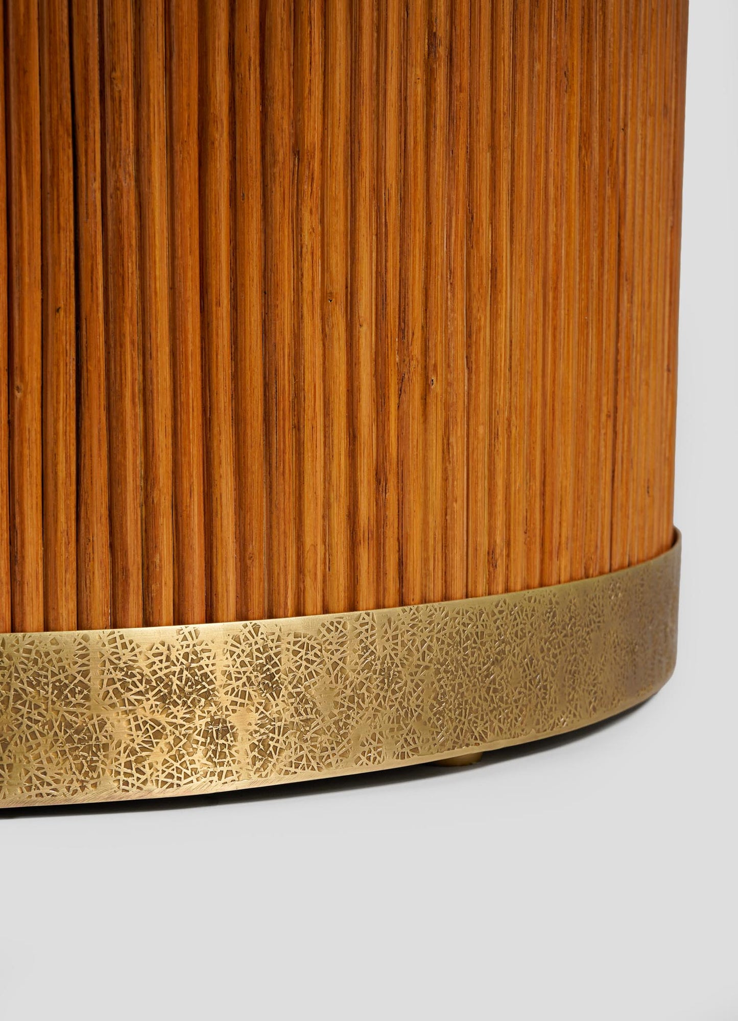 Close-up of the VIYA Namsai Dining Table’s cylindrical wooden leg with vertical grooves and decorative brass trim etched with intricate patterns, echoing classic Namsai style, set against a plain, light background.