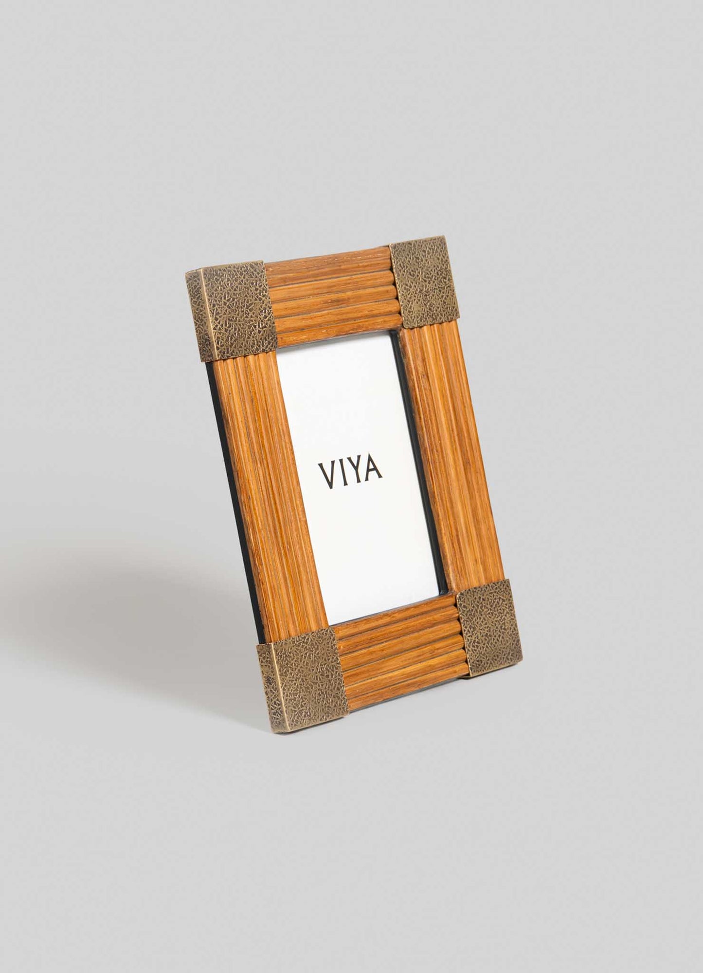 The Namsai Photo Frame Small by VIYA features textured brown corners and brass trimmings, showcased with a white card reading “VIYA” in black text, all set against a plain grey background.