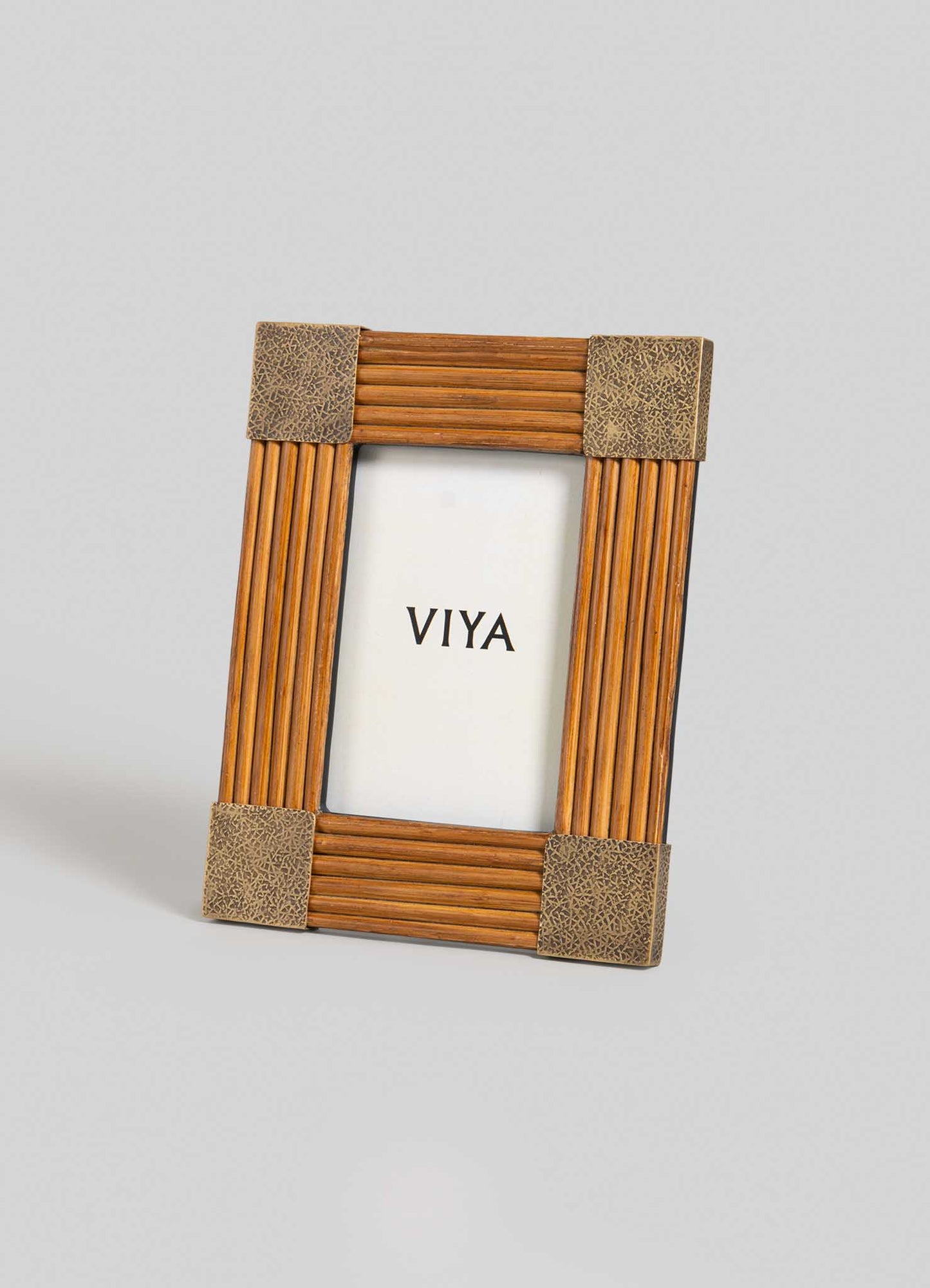 The VIYA Namsai Photo Frame Small stands upright with textured brown corners and brass accents, showcasing a white insert with "VIYA" in bold black at the center. The background is light gray.
