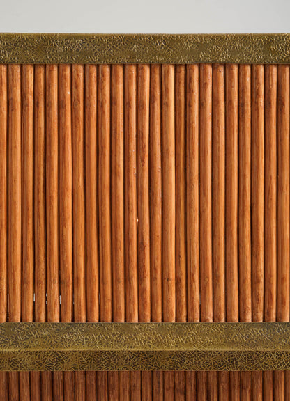 The Namsai Table Lamp Large by VIYA features vertical wooden rods with decorative brass trim at the top and bottom, forming a textured, symmetrical panel set against a neutral background.