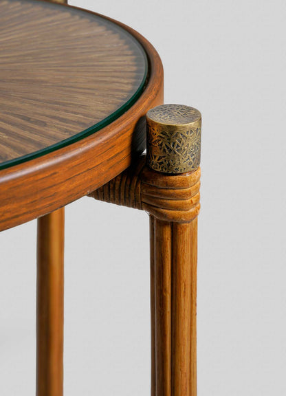 Close-up of the VIYA Namsai Tray Table Large, highlighting its round wooden structure with a glass top, intricate edge craftsmanship, and elegant brass-trimmed metallic cap atop one of its three legs.