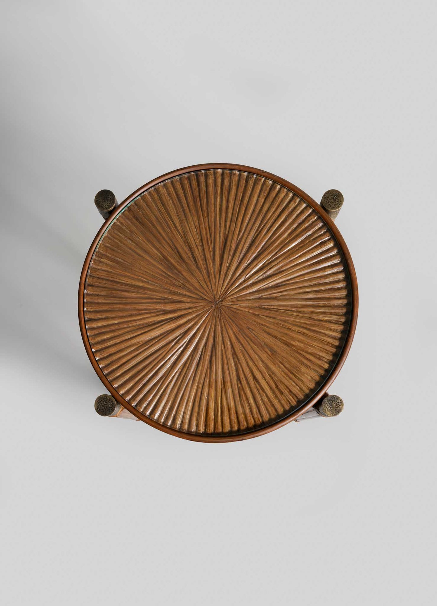 The VIYA Namsai Tray Table Tall features a round wooden top with an intricate, radiating pattern inspired by cane weaving, viewed from above against a light gray background. Four legs are partially visible at the edges.
