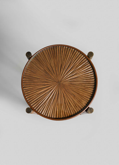 The VIYA Namsai Tray Table Tall features a round wooden top with an intricate, radiating pattern inspired by cane weaving, viewed from above against a light gray background. Four legs are partially visible at the edges.