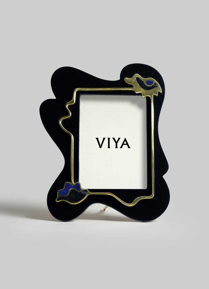 VIYA’s Nazar Black Photo Frame features an abstract black shape with gold outlining and blue accents, standing upright like a protective totem. "VIYA" is printed on a card inside, set against a plain light gray background.