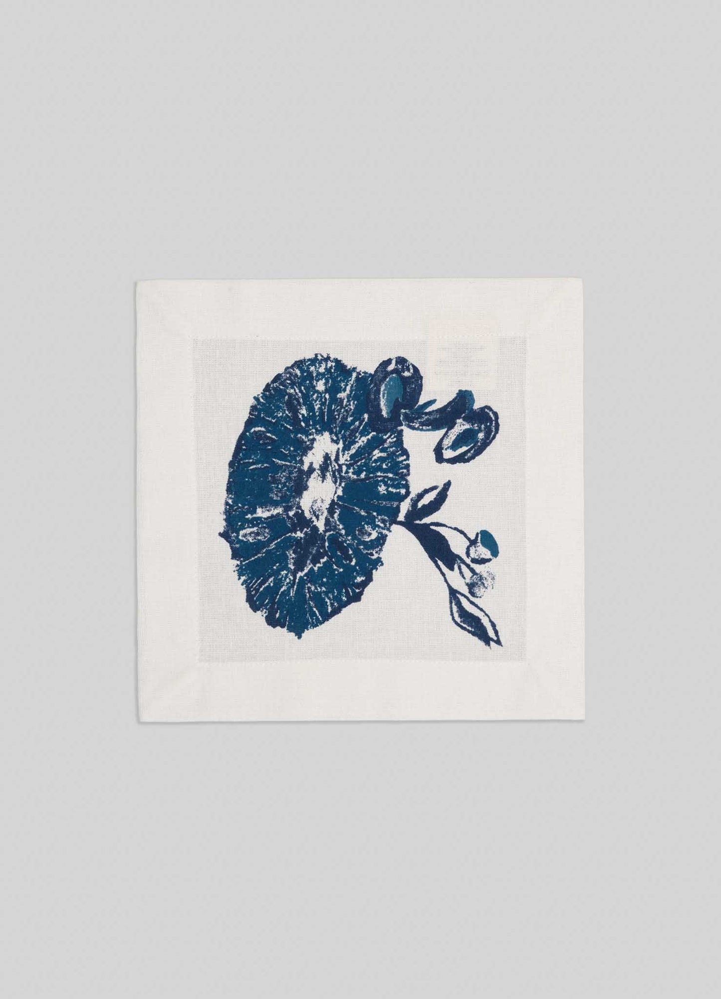 The Viya Orchard Blue Cocktail Napkins (Set of 4) feature a white base with blue botanical prints of round flowers and leafy branches, inspired by Indian pomegranates, set against a light gray background.