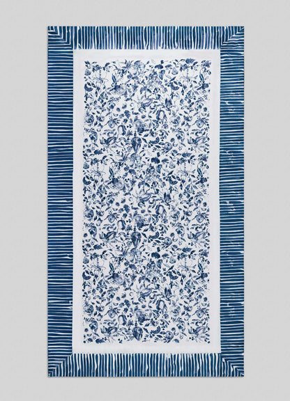 The Orchard Blue Table Cloth Large by Viya showcases a rectangular white design with a dense navy blue floral center, inspired by Indian orchard motifs, framed by wide blue and white stripes.
