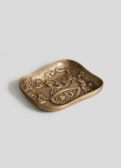A bronze-colored, rectangular Tiger & Hare Trinket Tray by VIYA with curved edges and raised dragon and floral patterns on its inner surface, displayed on a plain light gray background.