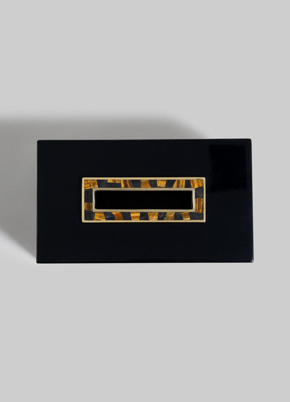 A rectangular, glossy black VIYA Plaza Tissue Box with an Art Deco-inspired gold and brown clasp, evoking Bombay's vintage cinema halls, is displayed against a plain grey background.