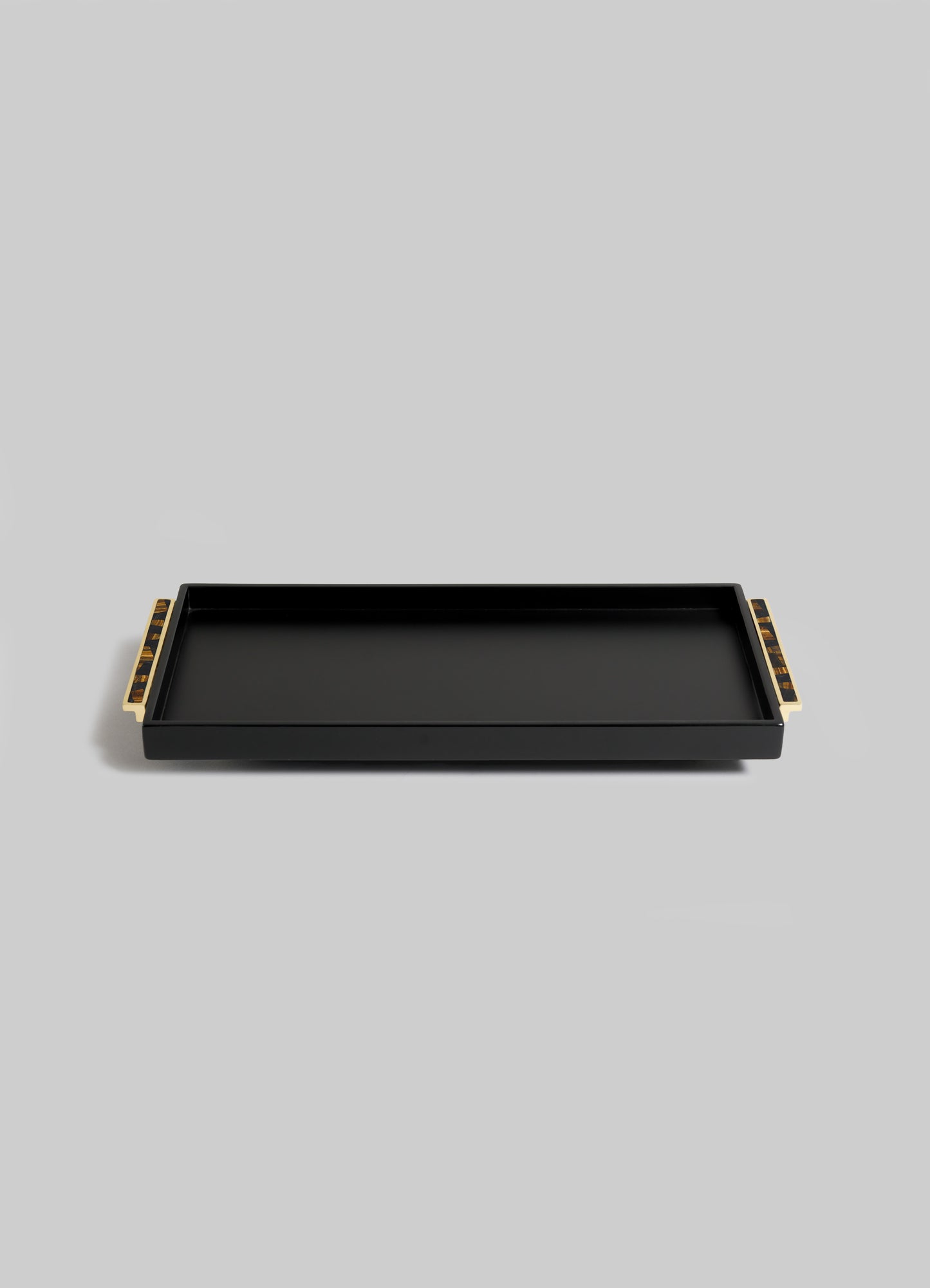The VIYA Plaza Vanity Tray, rectangular and black with raised edges and gold-tone handles, channels Art Deco elegance inspired by classic Bombay cinema halls. It's shown on a simple light gray background.