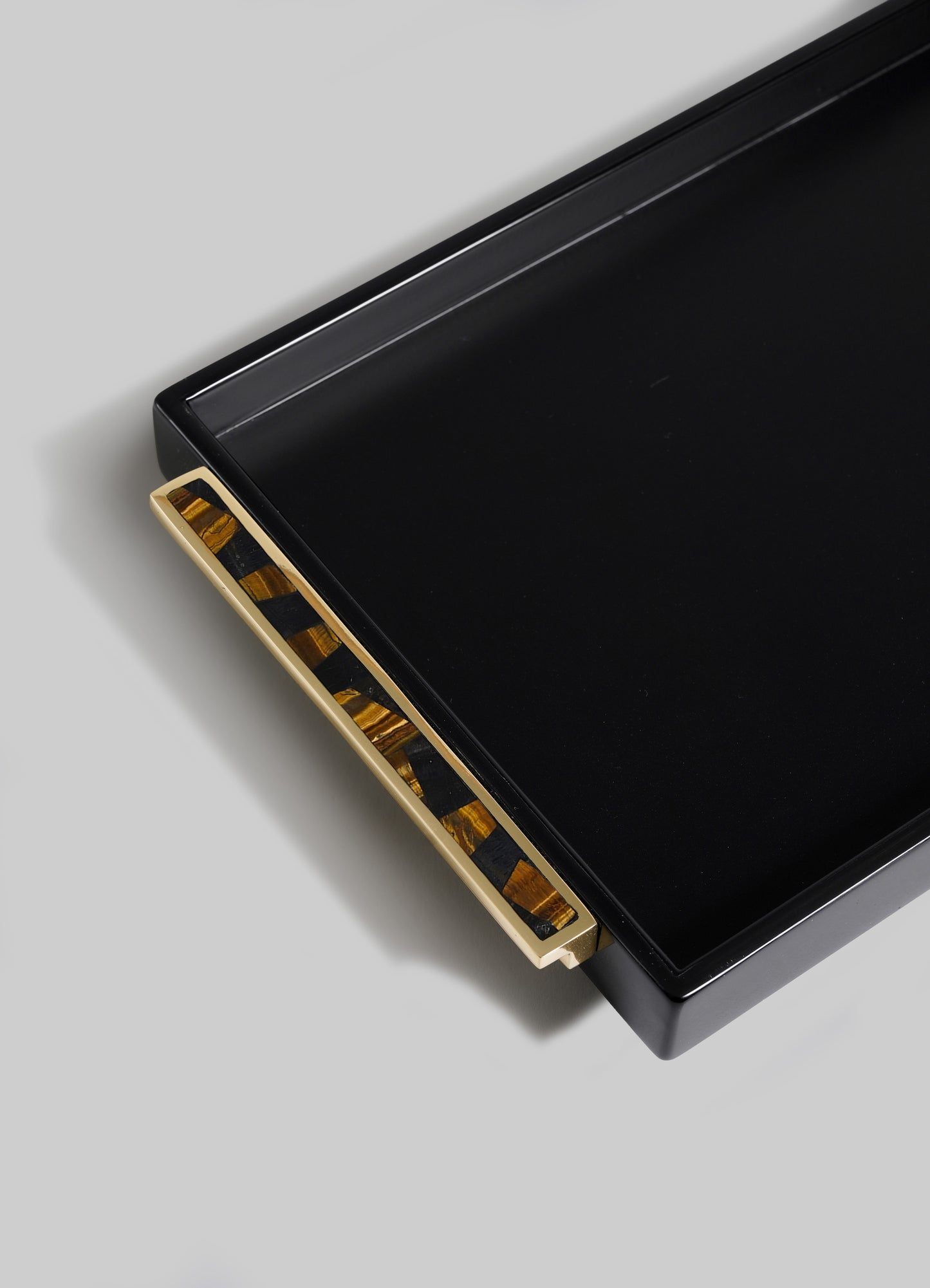 The VIYA Plaza Vanity Tray is a black rectangular tray with a gold and tortoiseshell-patterned handle, inspired by Art Deco designs from Bombay’s historic cinema halls, displayed on a light gray background.