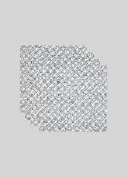 The Viya Paigah Navy Napkins - Set of 4 showcase a blue geometric circle pattern inspired by Hyderabad’s Indo-Islamic architecture, arranged in a slightly overlapping stack on a plain light gray background.