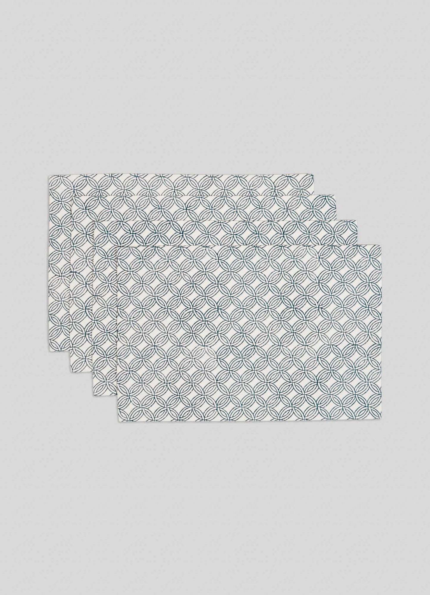 The Viya Paigah Navy Placemats - Set of 4 feature a repeating pattern inspired by Hyderabad’s Indo-Islamic jaalis, with overlapping navy and green circles on white, stacked slightly offset.