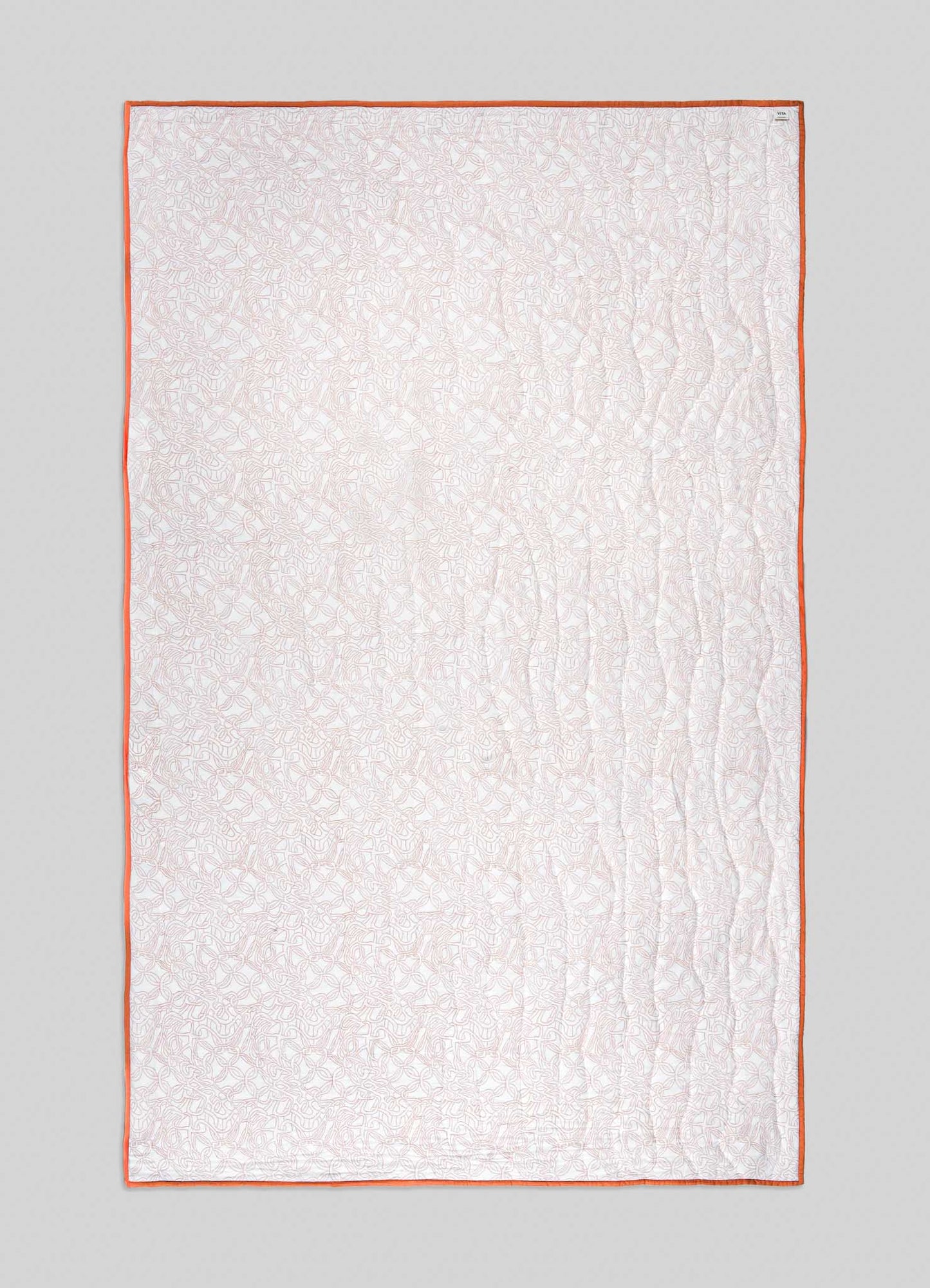 The Viya Paigah Orange & Blue Single Quilt is rectangular and light-colored, with an intricate lattice pattern, orange edging, and gentle wavy vertical stitches, displayed on a plain gray background.