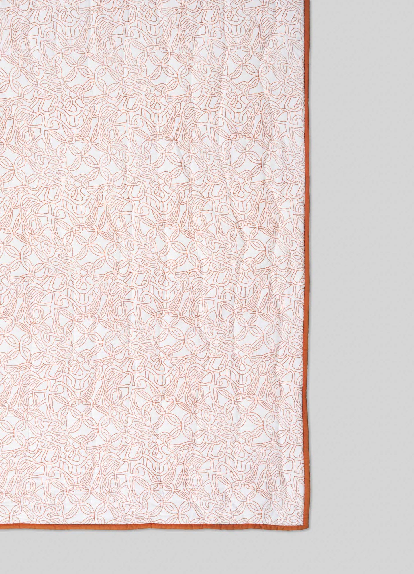 The Viya Paigah Orange & Blue Single Quilt features an intricate light brown abstract pattern inspired by paigah jaalis on white fabric, bordered with solid brown and set against a light gray background.