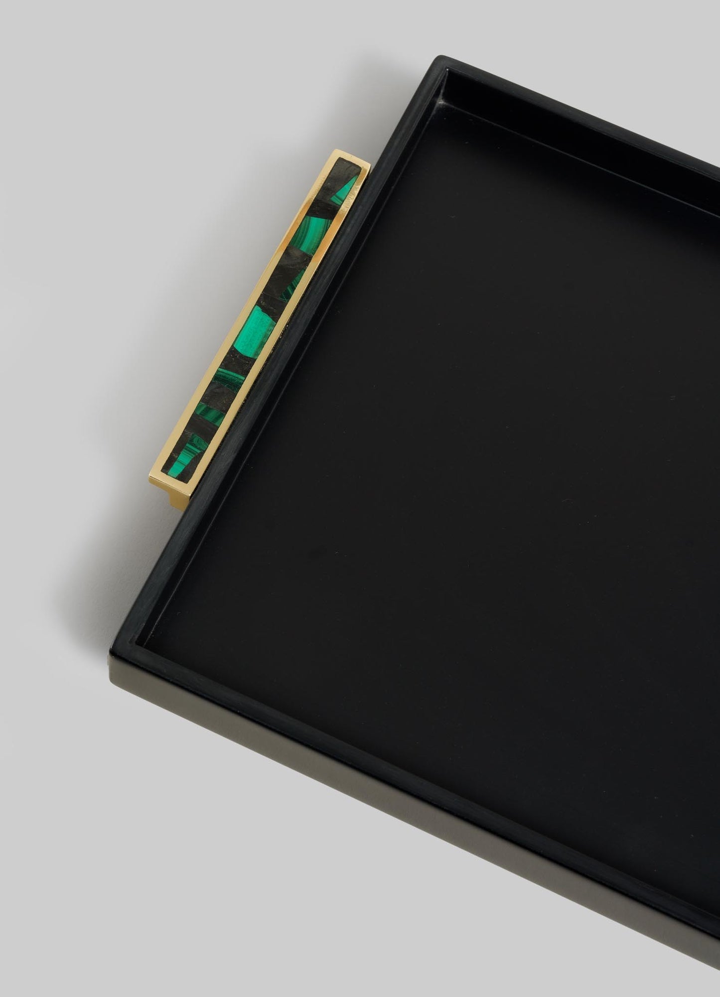 The VIYA Rivoli Black Towel Tray features a black rectangular design with a gold handle showcasing a green and black marbled inlay, inspired by Bombay’s Art Deco style, photographed against a light gray background.