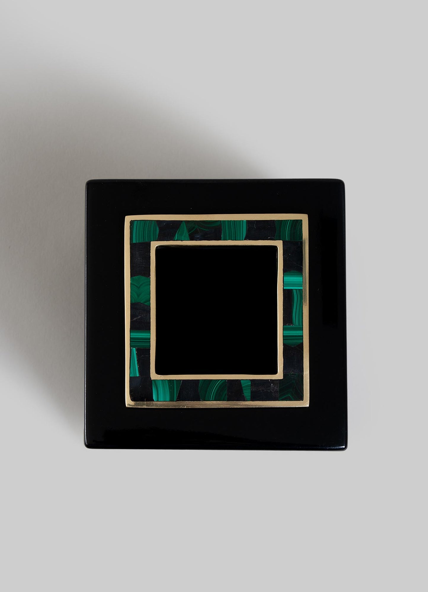 The VIYA Rivoli Cube Tissue Box features a glossy black square design with a decorative lid outlined in gold and bordered in green malachite, evoking Art Deco elegance. Shown against a plain light gray background.