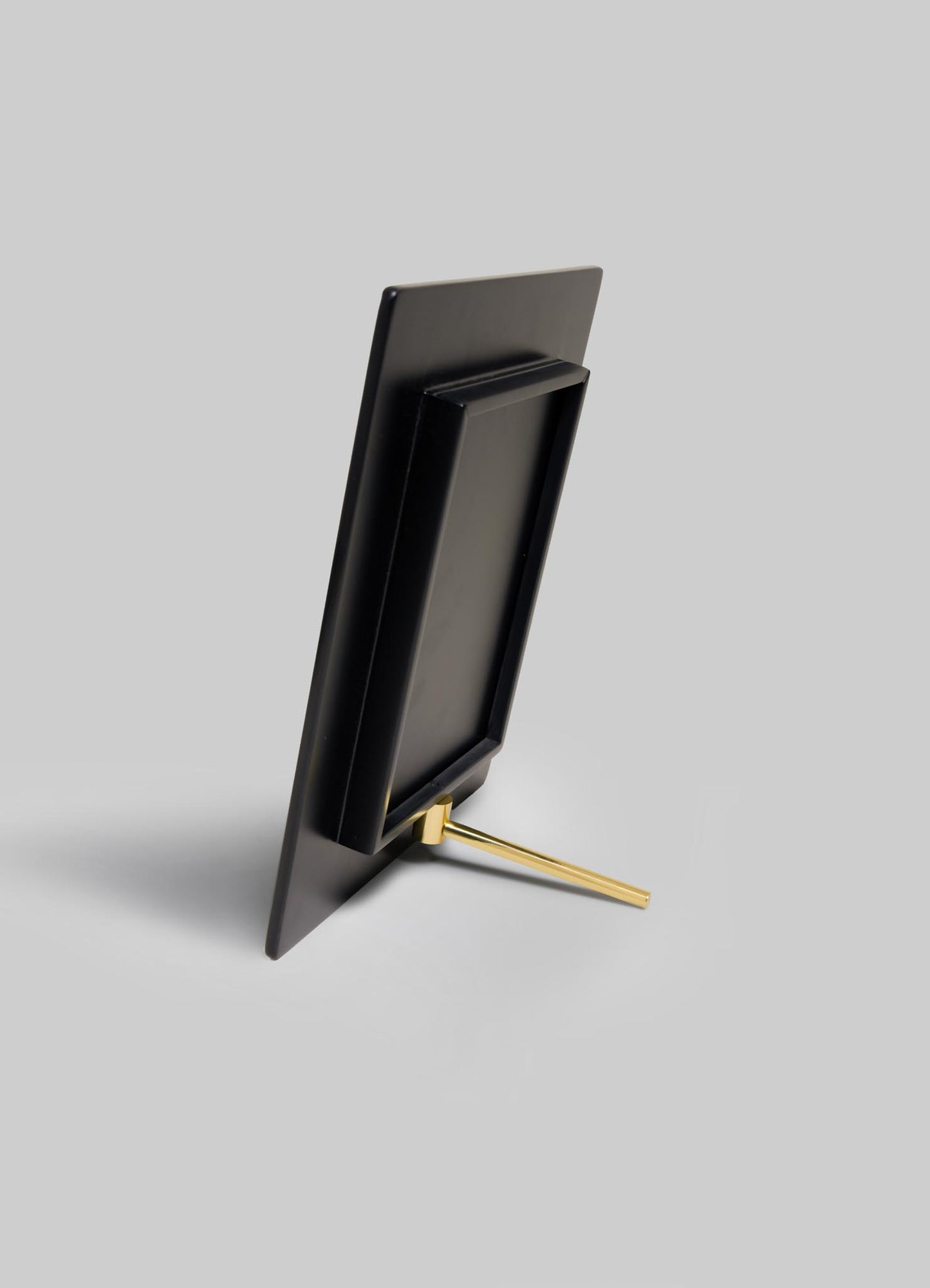 The VIYA Rivoli Photo Frame, inspired by Art Deco details from old Bombay cinema halls, is shown in black with a gold stand on a light gray background. The empty frame is vertically oriented and displayed from the back.