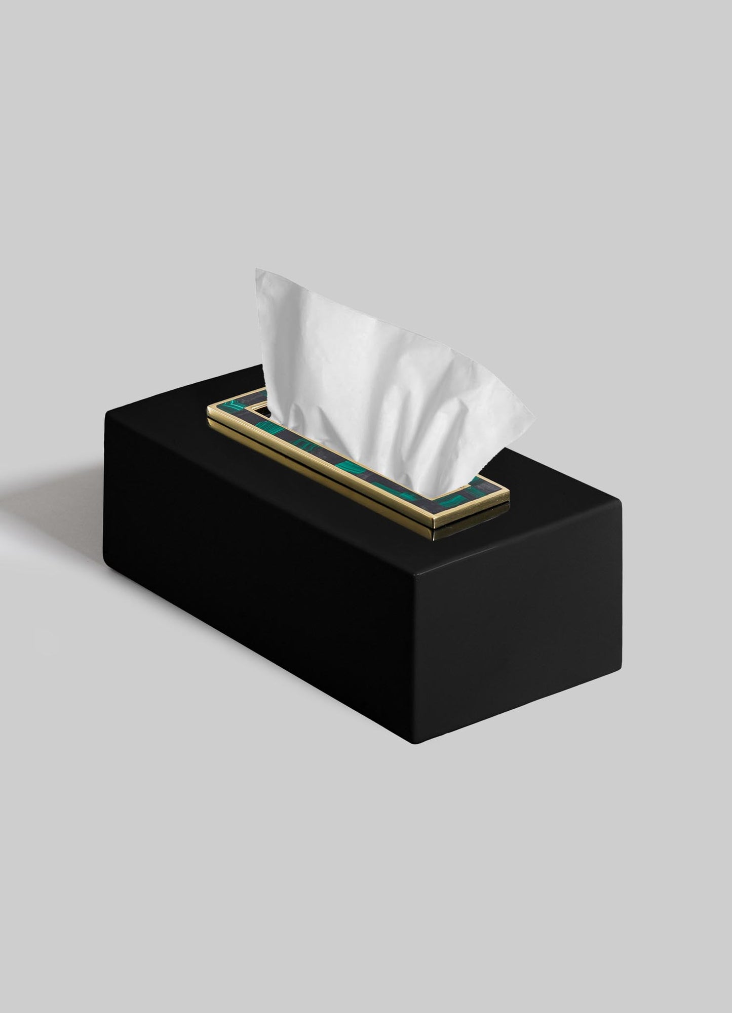 The VIYA Rivoli Tissue Box features a black rectangular design with a gold-trimmed opening, echoing Art Deco elegance, and displays a single white tissue against a plain gray background.