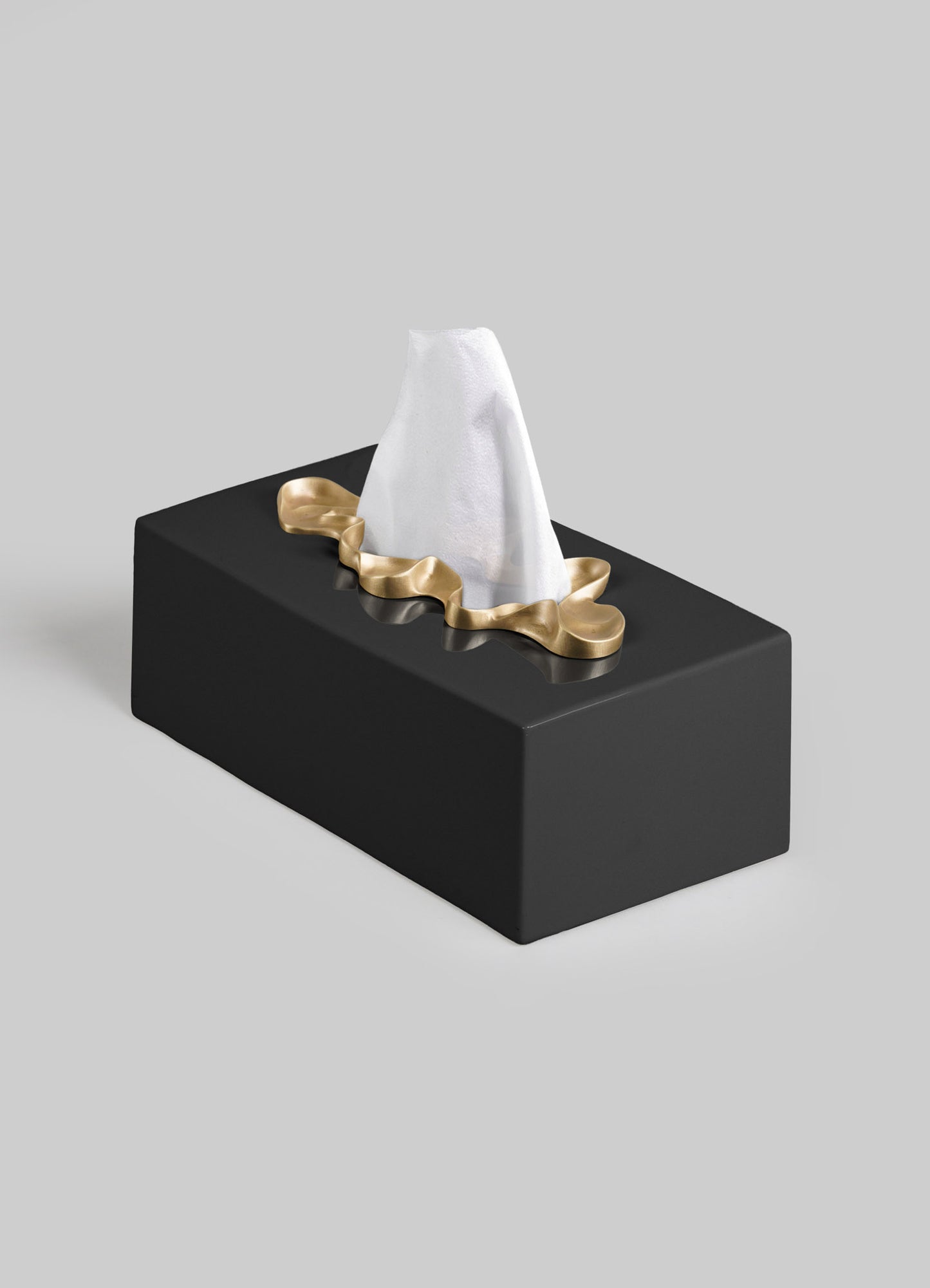 The VIYA Saffron Black Tissue Box Large features a rectangular black design with a gold, wavy-edged opening, holding a single white tissue atop a plain light gray background, evoking the look of contemporary bronzed objects.