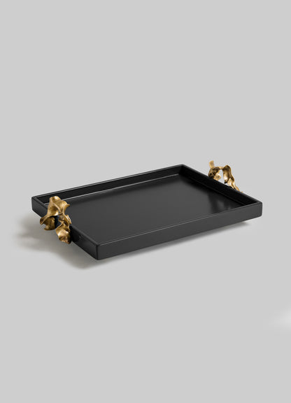 The VIYA Saffron Black Towel Tray features a rectangular black design with two gold handles shaped like abstract, contemporary bronzed forms, displayed against a light gray background.